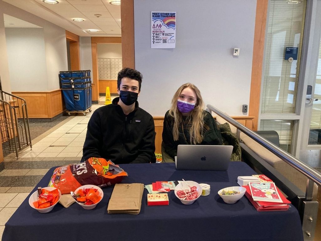 two operation assistants sitting at a hub desk that is decorated with valentines day decorations. The operation assistants are giving out candy