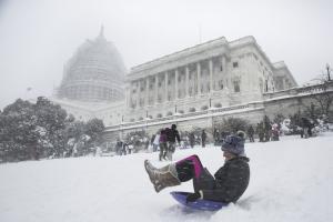 A student plays in the snow in front of the Capitol