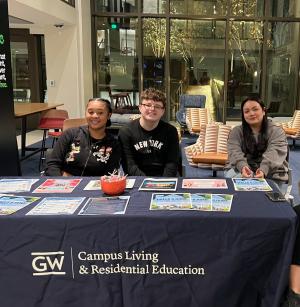 A group of CLRE student staff (CEAs and CEAds) have fun working a shift, and sit together at an event table passing out CLRE branded materials