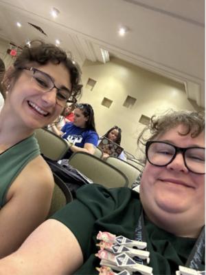 Two GW CLRE Staff Members sit and smile together at a Residence Hall Association Event. 